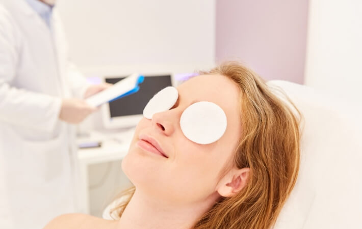Woman in the optometrist's office sitting on a chair with a warm cotton compress on each eye.