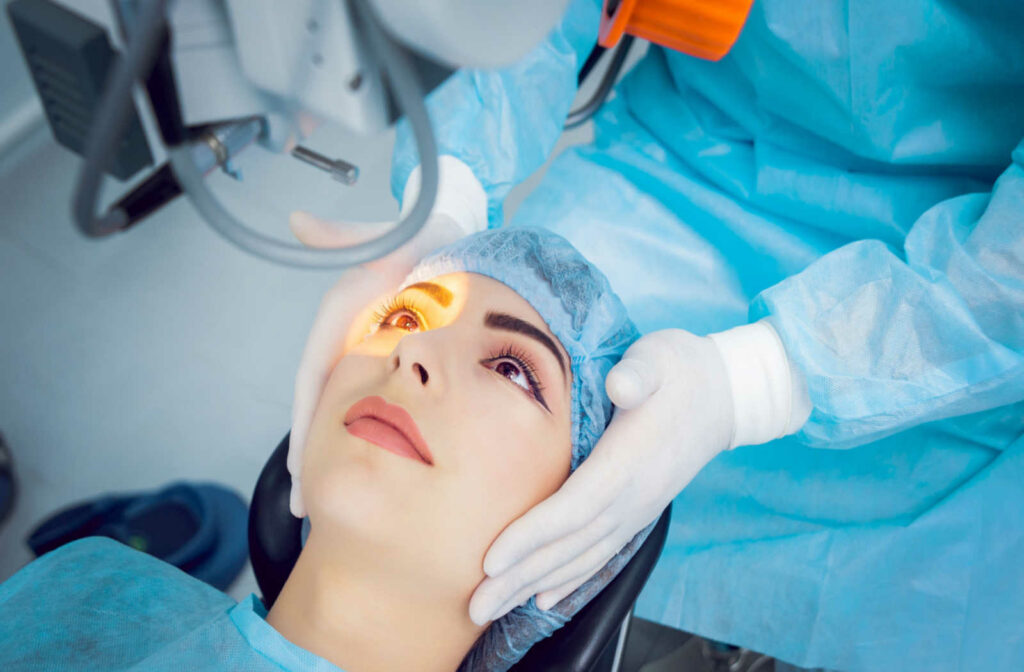 A surgeon adjusts a woman's placement under the laser as she wears a surgical gown and hair cover.