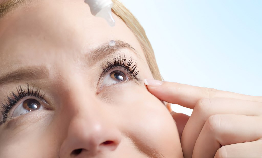 Close up of woman administering eye drops to treat dry eyes.